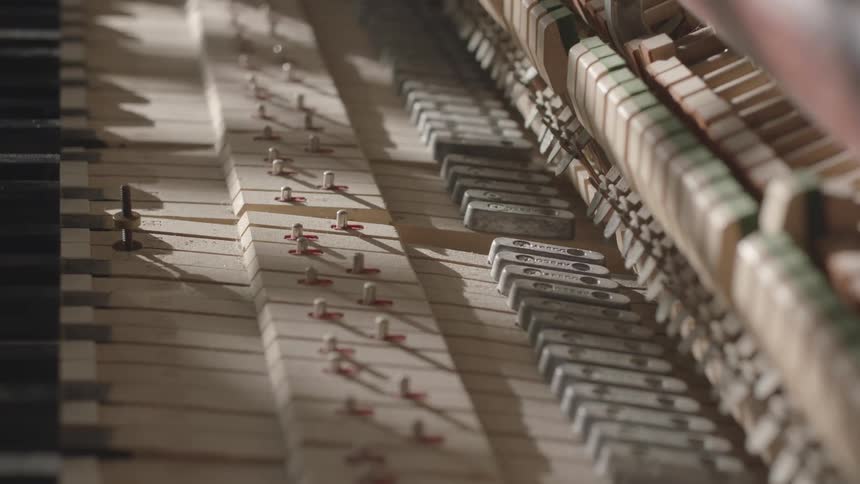 Close up of the inside of a piano with keys moving