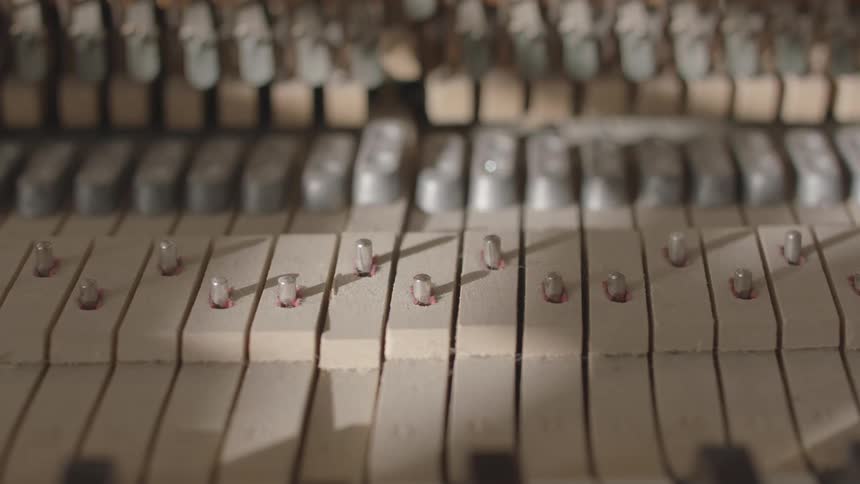 Close up of the inside of a piano with the wooden keys moving