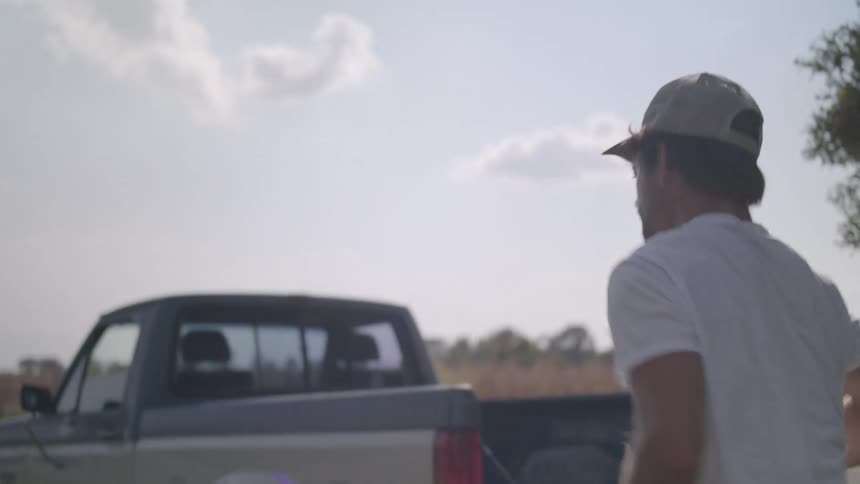 A man is loading logs into the bed of his truck
