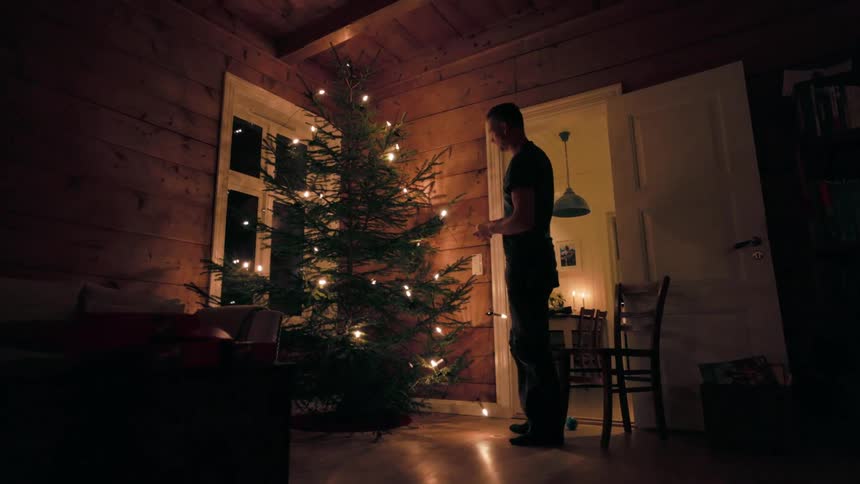Man decorating a christmas tree with lights at night