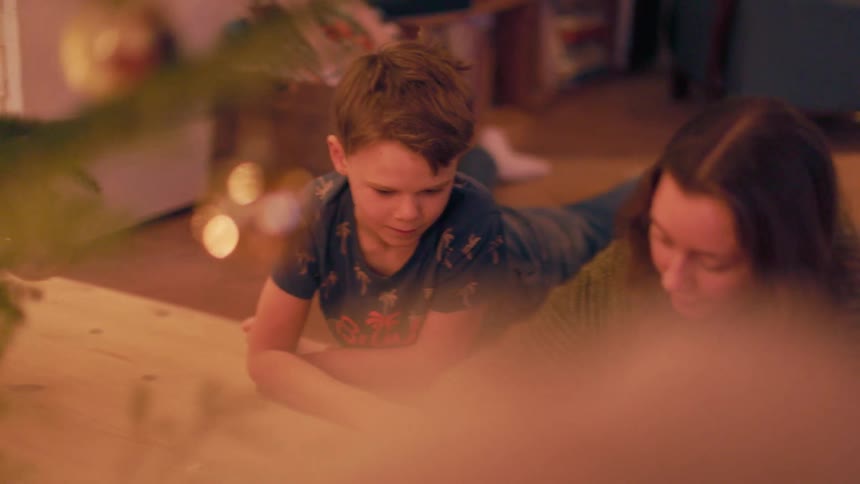 Woman and a child lying in front of a christmas tree