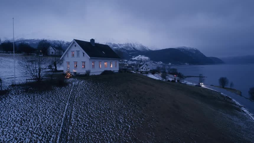 House on a hill by the sea with snowy mountains in the background