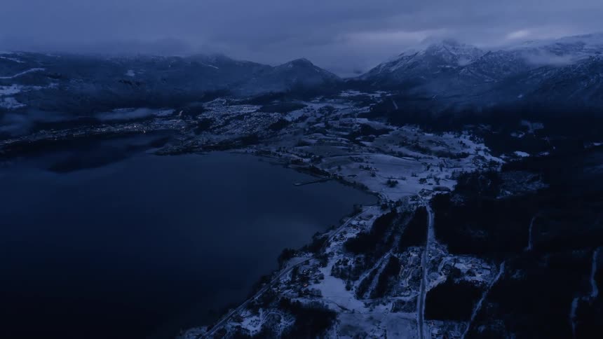 Aerial panorama of a lake surrounded by mountains and a picturesque snowy town
