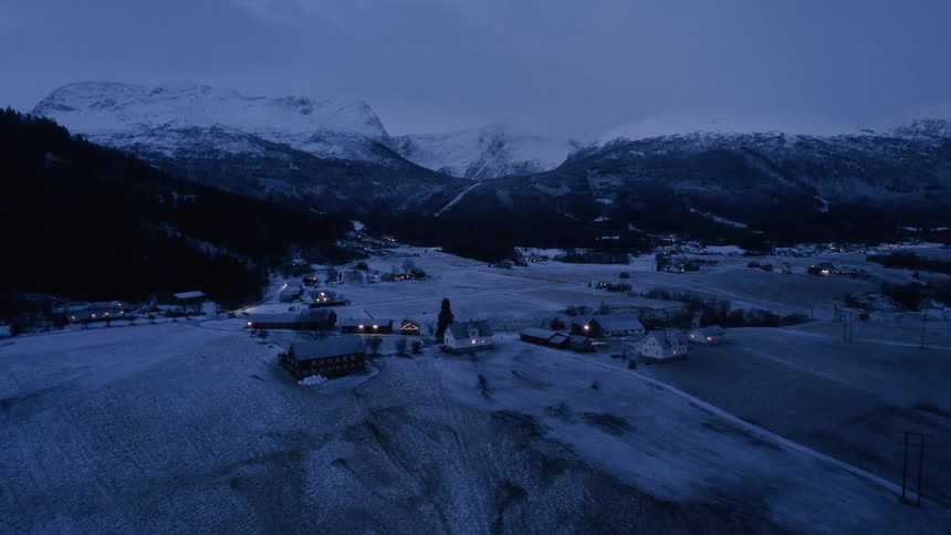 Aerial shot of rural houses surrounded by snowy mountains