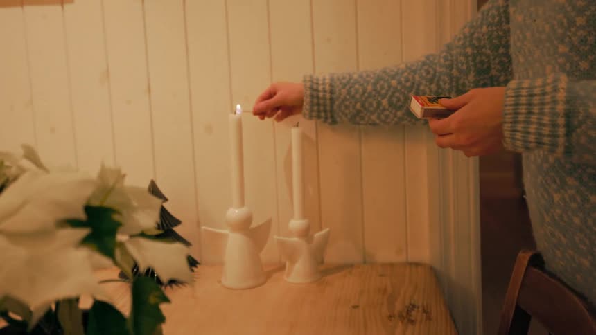 Person with match lighting a candle