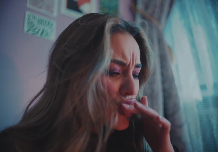 The face of a blonde woman who is putting her finger in her mouth after touching something hot