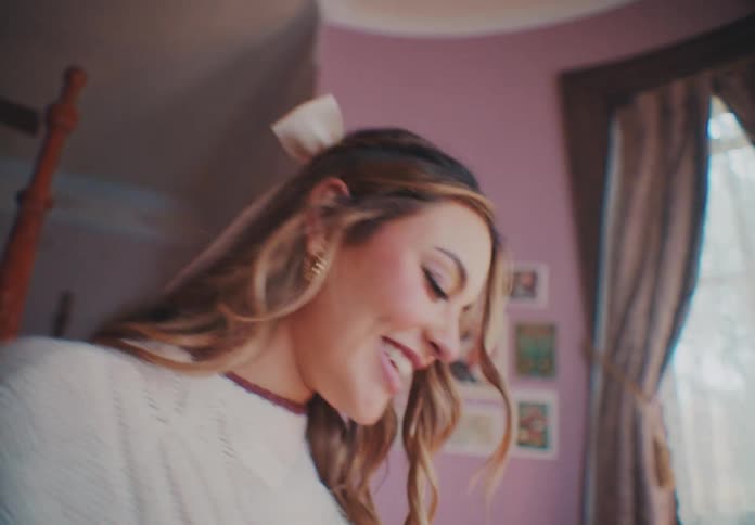 A young woman dances and smiles in her room at midday