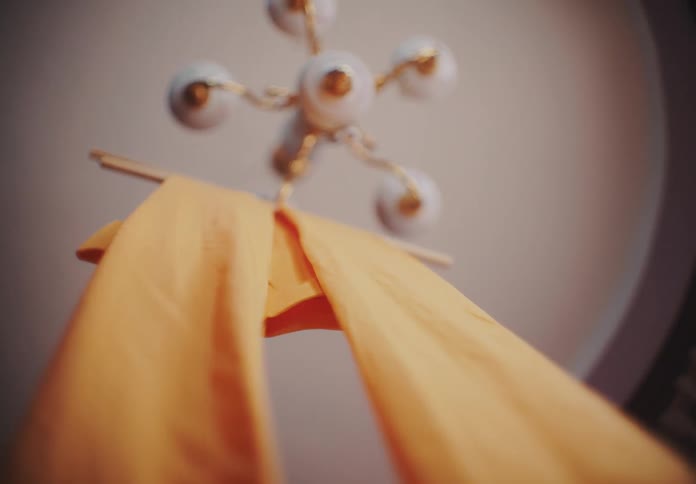 A piece of orange cloth stuck to a chandelier that is on the ceiling spinning