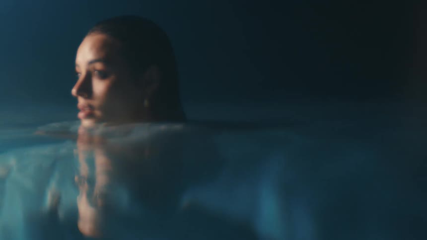 The face of a young woman who has her body in the water in a dark environment