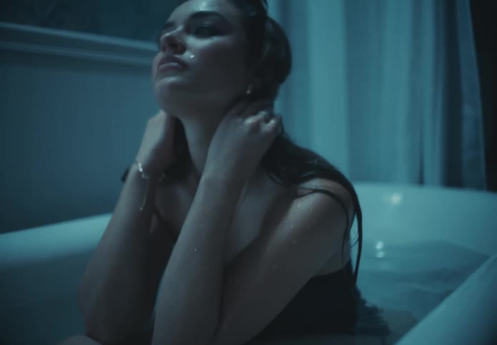 Woman sitting in the bathtub while dressed angrily hits the water