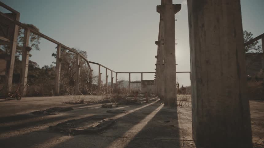 A wide shot of an abandoned industrial structure casting long shadows under the midday sun