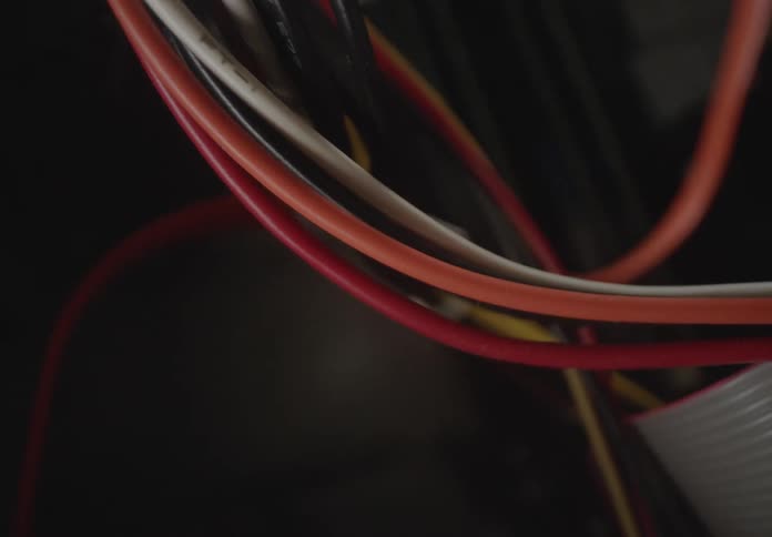 A closeup of a bundle of vibrant tangled wires set against a deep shadowy backdrop