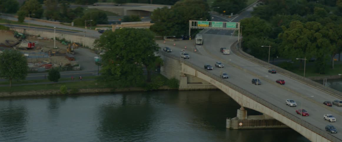 Traffic moving on a bridge above a body of water surrounded by trees