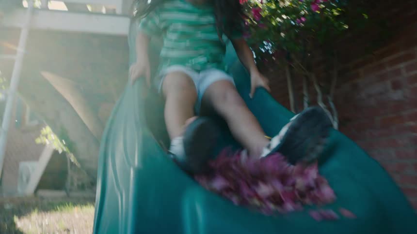 Girl going down the slide with pink flowers