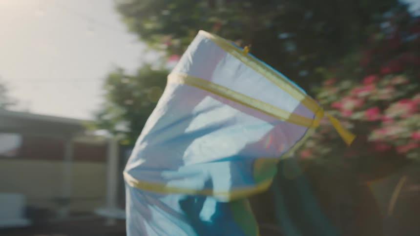 Two children with a colorful toy bag on their bodies running through the backyard of a house