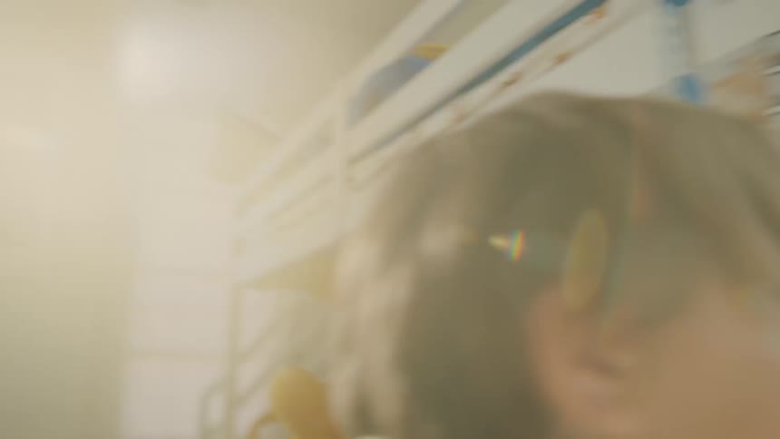 During a game of hide and seek a boy uncovers people hidden under a blanket in a bright colorful room filled with sunlight