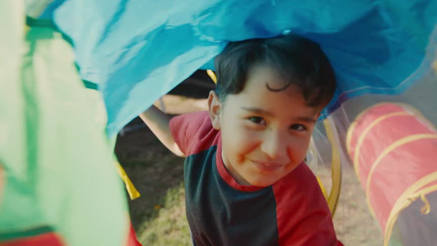 Happy boy entering inside a colorful toy in the backyard