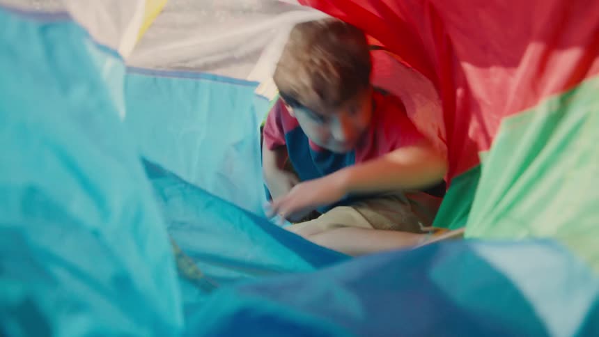 A boy crawls through the colorful tube