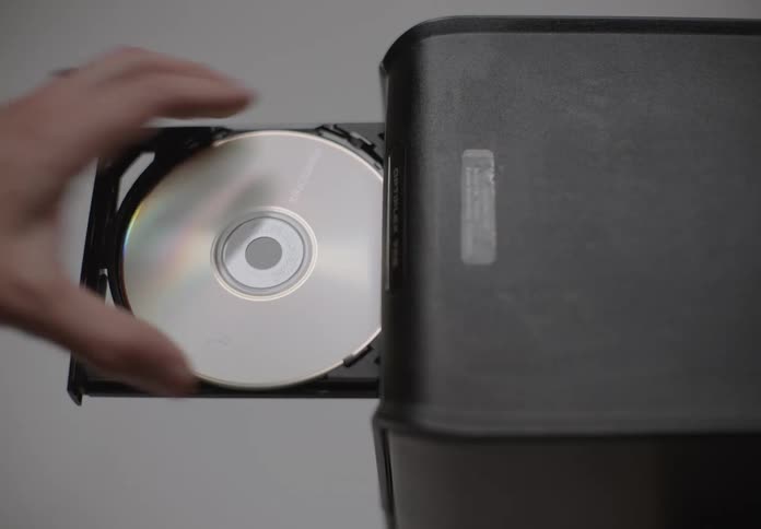 A person presses the button to open a computers internal cd drive and then removes the cd