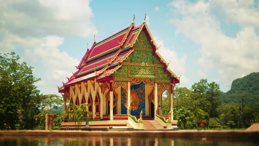 An indian religious temple near a lake with many trees around it