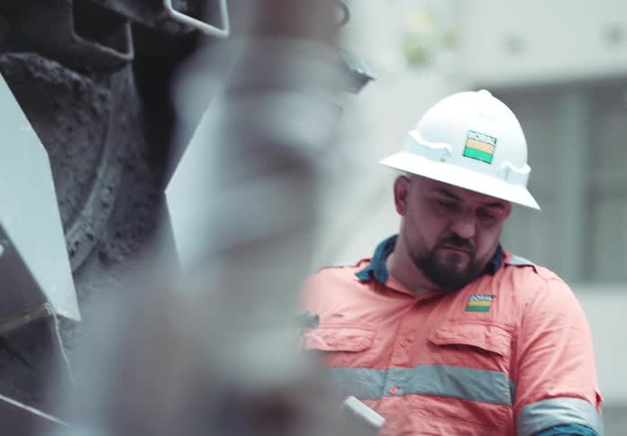 Man in helmet working with a machine that is pouring concrete