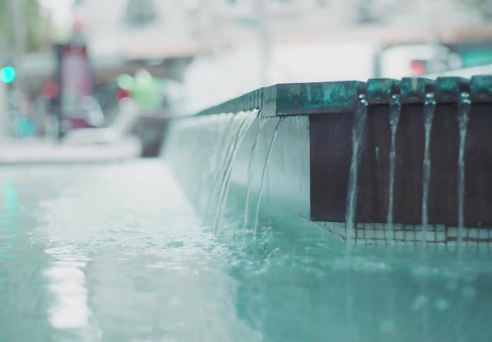 The fountain in the city pours water into a pool