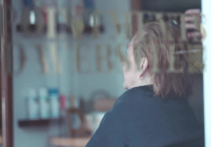 Client gestures and talks while the beautician dries her hair