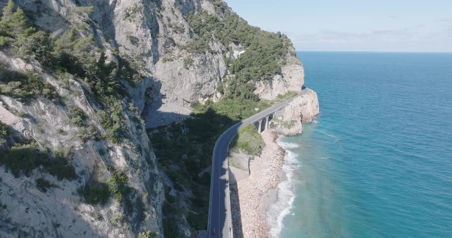 A long road is on the side of the mountain near the ocean