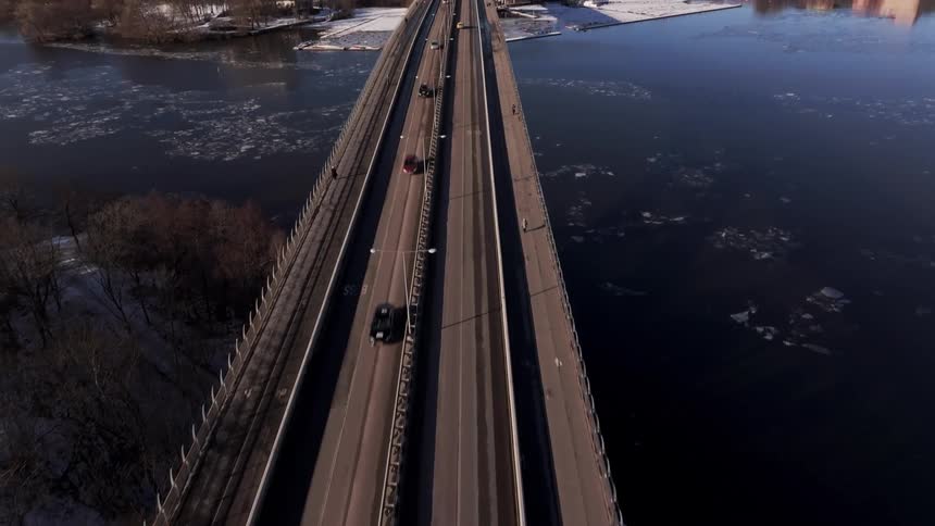A bridge with cars in traffic leading to a metropolis over a river