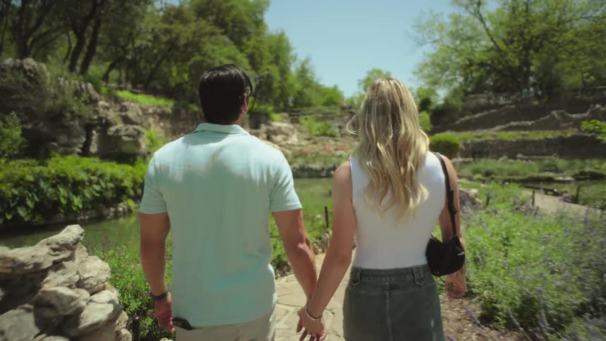 A couple hold hands while walking through the park