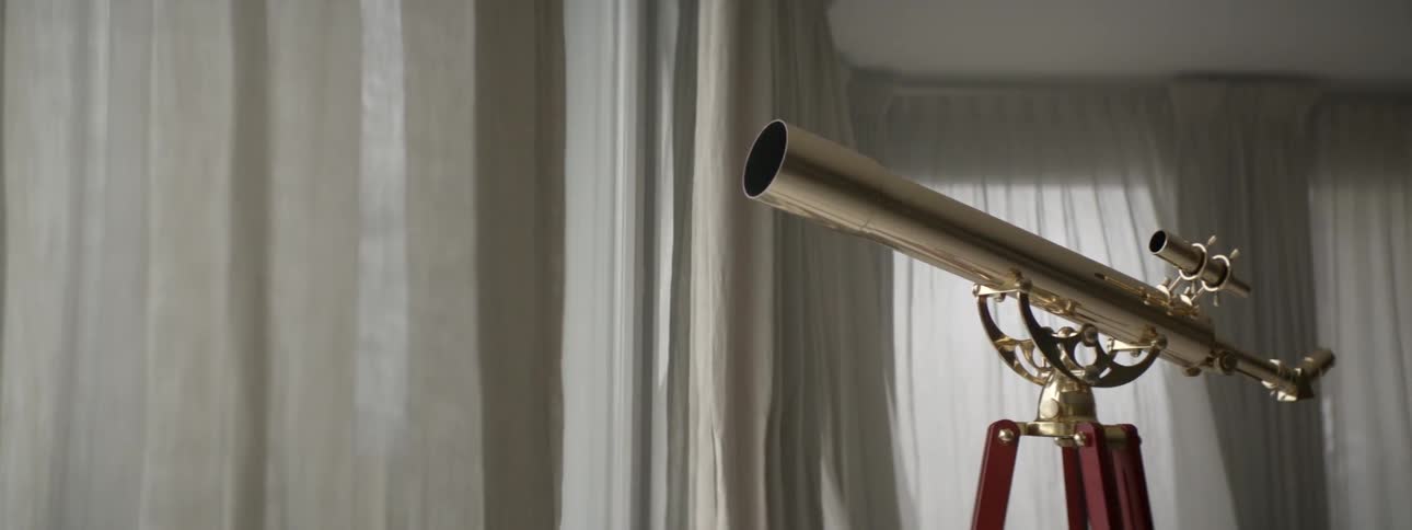 A gold telescope is pointing at the window