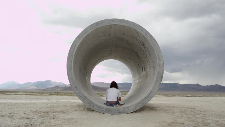 A woman sits in a concrete pipe
