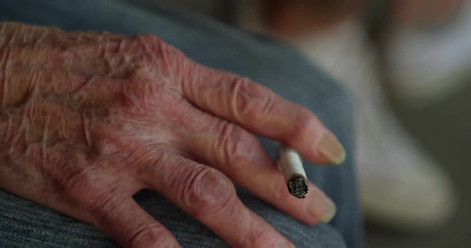 Older person holding a lit cigarette