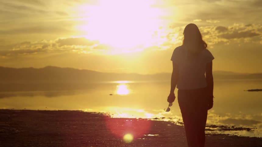 A woman is walking on the beach at dawn