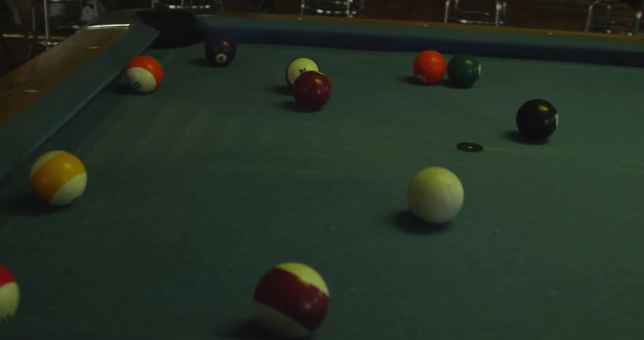 A person hits a pool ball on a pool table