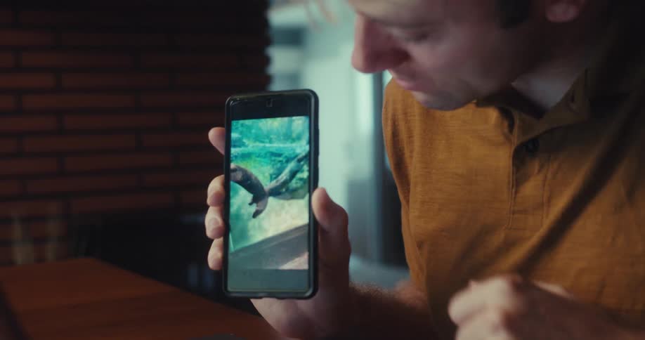 A man showing a cellphone with some photos on the screen