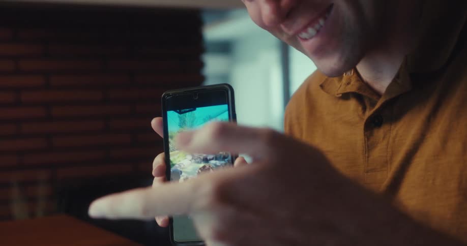 Portrait of a cheerful man showing a photograph on a smartphone