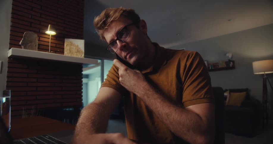 Man writing on a document while talking on his cell phone