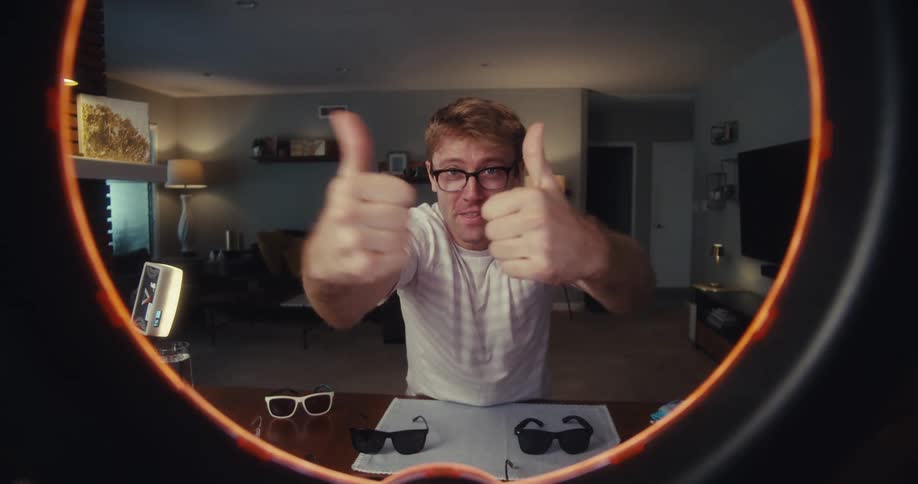 Cheerful man making hand gestures sitting at a table with sunglasses