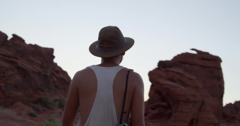 A man carrying a camera walks in the desert