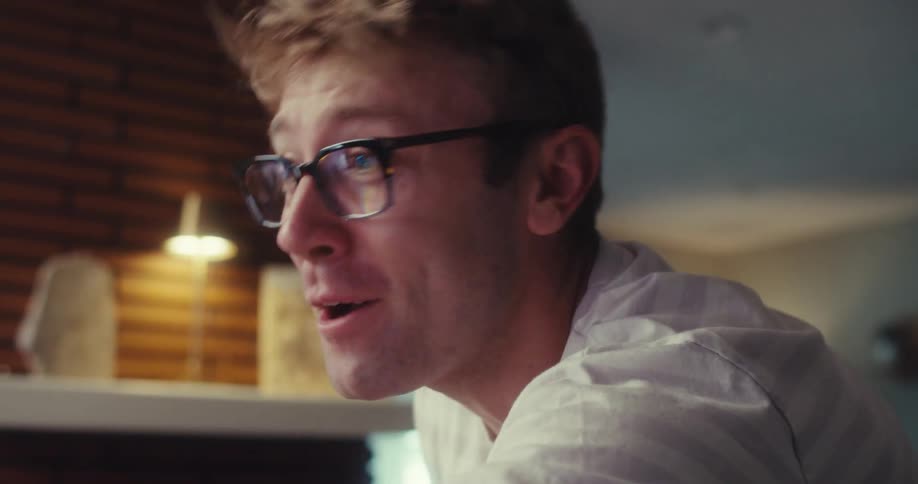 A man joyfully records himself using a smartphone in front of a ring light vlogging with excitement