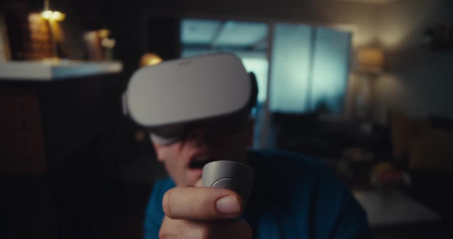 A man wearing a vr headset is filled with excitement while in his sitting room