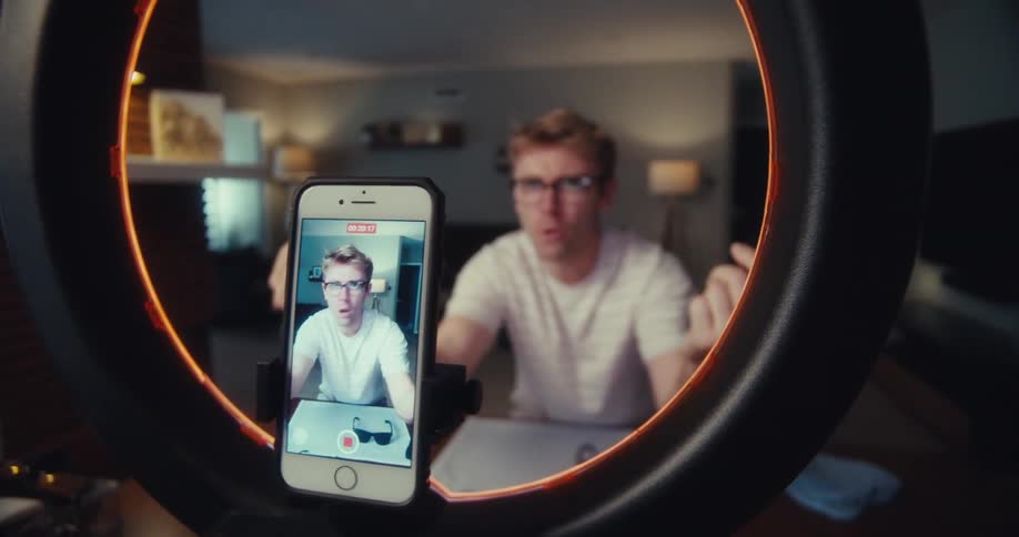 A man is showing off glasses to the camera while he talks about them
