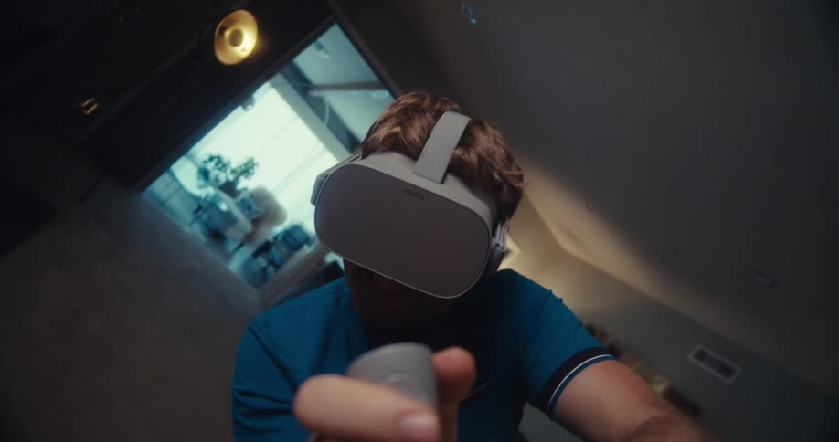 A young person wearing a vr headset plays enthusiastically in a dimly lit living room