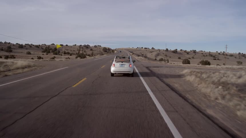 A small car signals then turns onto a side road in the desert