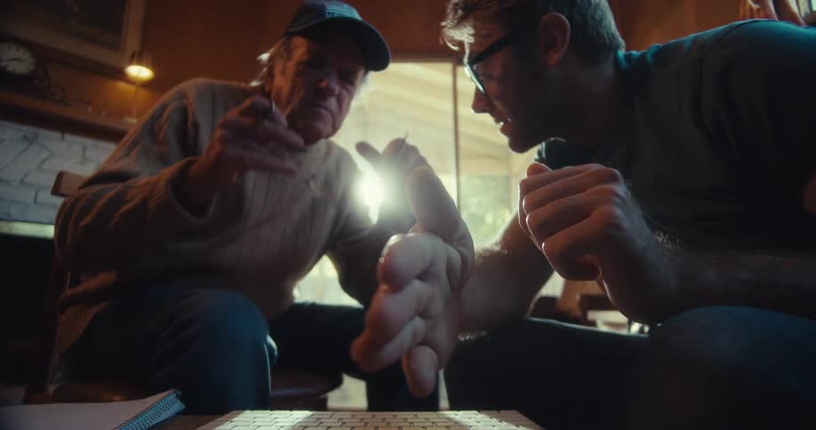 Man and an elderly man sitting talking and pointing in a direction