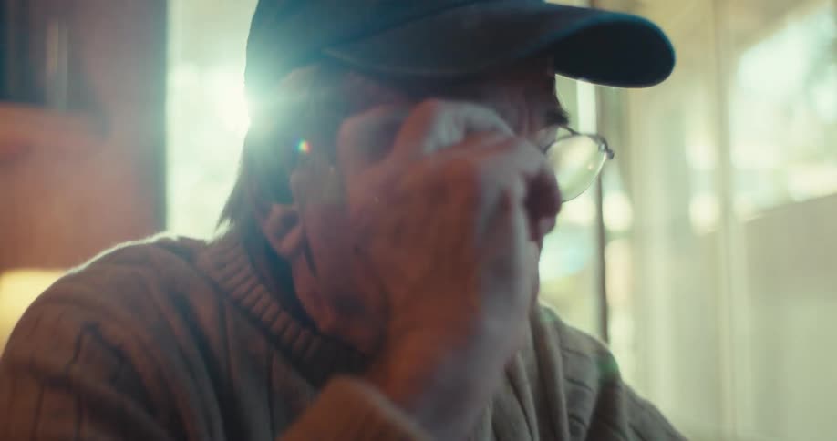 A man puts on his glasses while talking