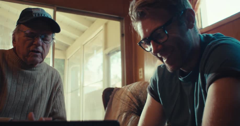 A man talks with another man while looking at the laptop