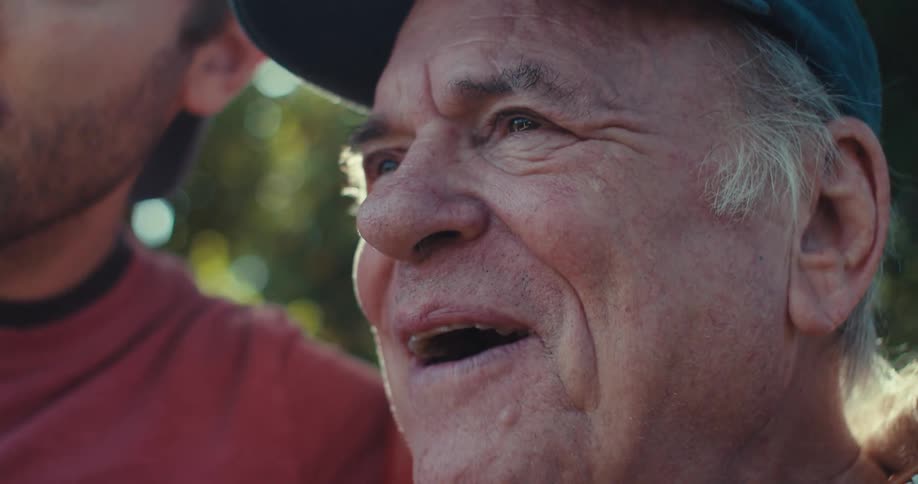 Man talking to an elderly man in a backyard with trees