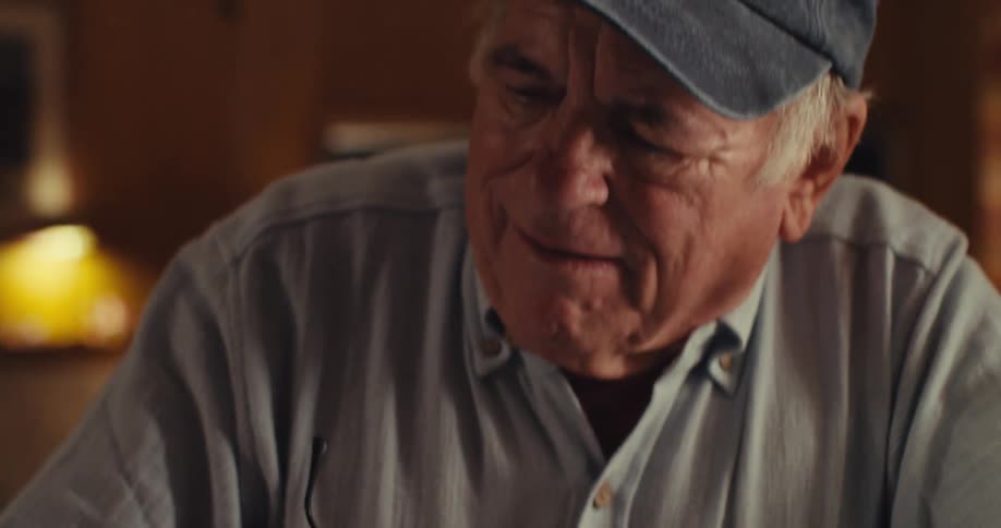Man in shirt writes with pen while holding glasses